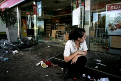 An employee sits amidst a ransacked gas station after looters stole from it
